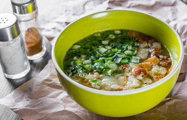 Chicken soup with green onion and croutons in bowl on wooden table