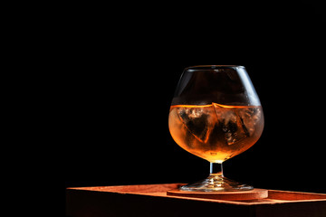 Close-up brandy glass filled with whiskey with ice.