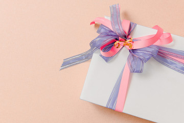Luxury box tied with blue and pink ribbons on pink background