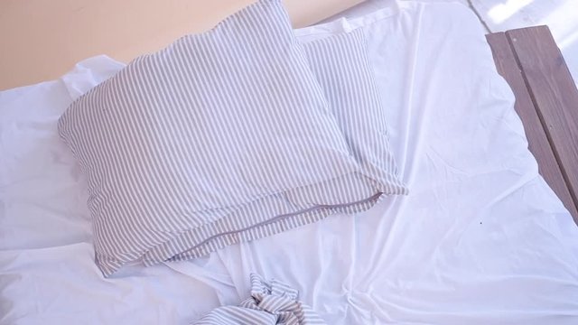 New day beginning. Morning habits. Top view of unmade, messy empty bed. Modern striped bed linen.