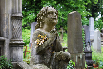 Scene in a cemetery: statue of a girl kneeling, praying