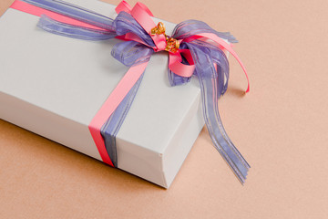 Luxury box tied with blue and pink ribbons on pink background