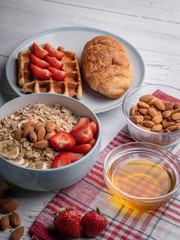 Traditional breakfast with sweet belgian waffles and oatmeal porridge. Homemade croissant, berry, honey and almond. Close up delicious dessert on white background