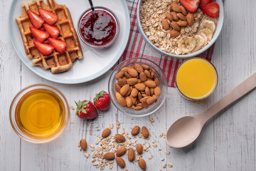 Breakfast. Oatmeal or muesli. Morning food. Snack. Belgian wafer with strawberry, honey, almond, juice on white background. Top view