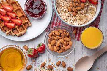 Breakfast. Oatmeal or muesli. Morning food. Snack. Belgian wafer with strawberry, honey, almond, juice on white background. Top view