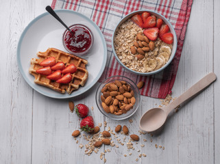 Breakfast. Oatmeal or muesli. Morning food. Snack. Belgian wafer with strawberry, honey, almond, juice on white background. Top view