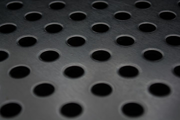 Gray monophonic background with big quantity of holes in a metal plate. Surface. Texture.