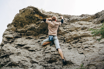 Brave young man climbs the top of the cliff