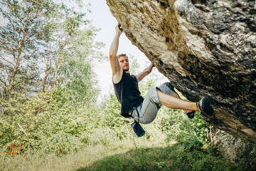 Naklejka na ściany i meble Male rock climber hanging on the cliff