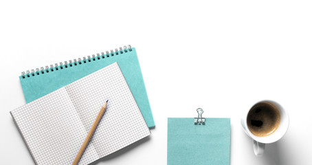 White designer office desk table with turquoise Notebook, pencil, envelope and a cup coffee . Top...