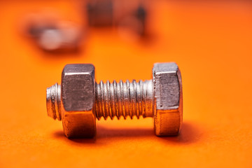 Bolted connecting elements on orange background close-up