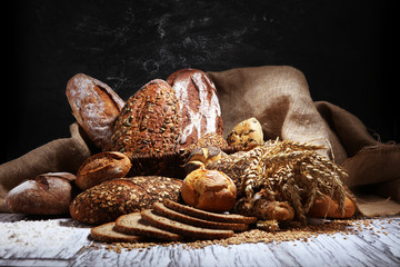 Assortment of baked bread and bread rolls on rustic white bakery table background