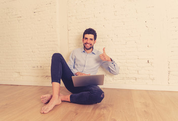 Hipster young man on laptop in his new empty apartment searching on the internet buying furniture