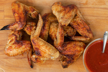 Chicken wings with red sauce on wooden table