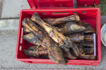 Smoked pig feet with a hoof in a crate in market