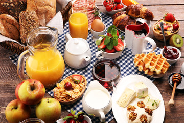Huge healthy breakfast on table with coffee, orange juice, fruits, waffles and croissants. Good morning concept.
