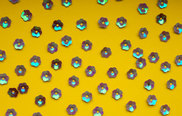 Floral purple confetti on yellow background, top view, seamless pattern. Creative summer texture.