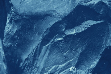 Vintage blue background. Rough painted wall of sapphire color. Imperfect plane of blue colored. Uneven old decorative toned backdrop of cyan tint. Texture of sapphirine hue. Ornamental stony surface.
