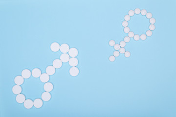 Symbols of masculine and feminine pills on blue background. Concept for genders, feminine and masculine, man and woman, boy and girl. Feminine and masculine principles are symbolic symbols laid.