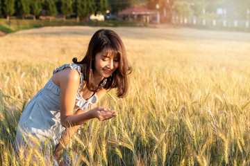 Beautiful and happy asian woman enjoying life in barley field at sunset.