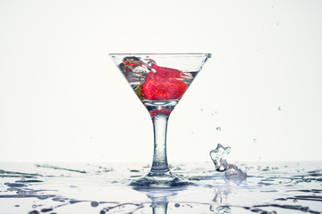Frozen explosion of freshness from water, in a cocktail glass with strawberries, on a white background.