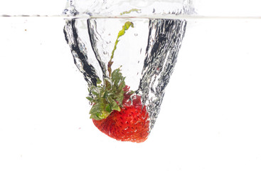 Red fresh strawberries thrown into the water, under water. Spat and splash