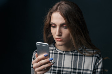 Sad teen being victim of cyber bullying online sitting on a couch in the living room at home