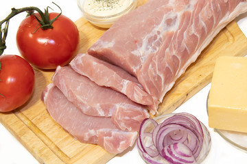 Pork chop isolated on white background. Meat on a white background. Raw meat and red tomatoes. Tomatoes on the branch.