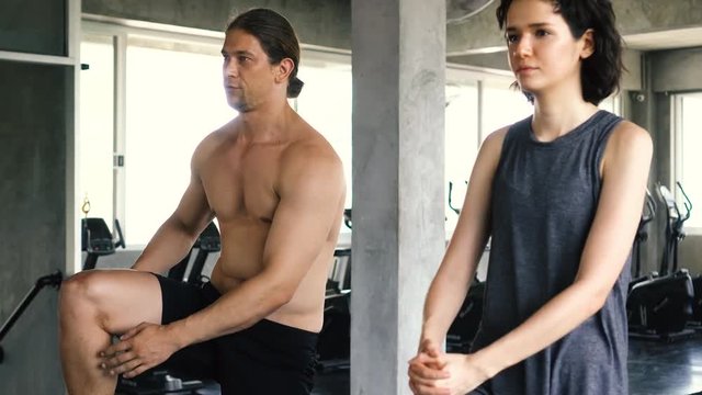 Young woman and man stretching their legs on the gym floor. Two people couple working out indoors