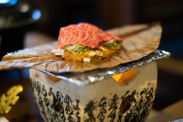 Charcoal grilled hida beef on oba leaf with miso and vegetables, traditional food at Takayama, Japan.