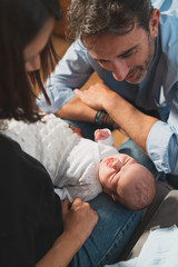 Obraz premium Top view of a cute adorable baby sleeping with open arms on her mother and father. Family, new life, childhood, beginning concept.