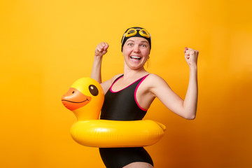 Photo of strong woman in swimsuit with life preserver on empty orange background
