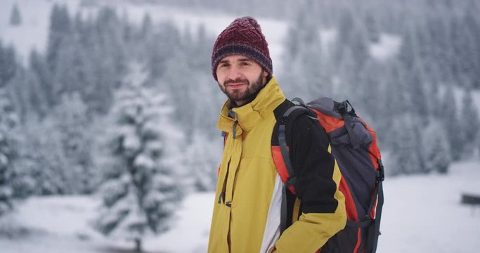Smiling large happy tourist man in front of the camera he traveling in the mountain , in the winter amazing landscape around snowy forest