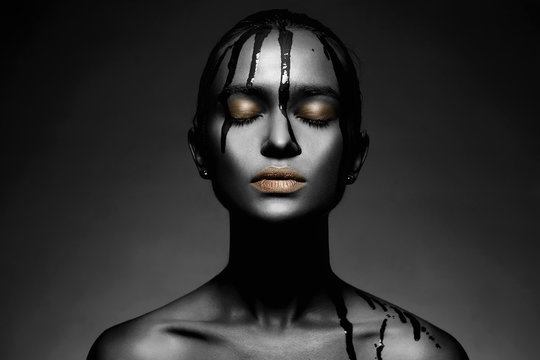 Young woman in black paint with golden lips
