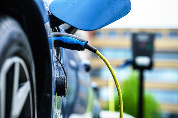 Electric Car is charging on street docking station on parking Lot