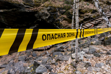 Danger zone in cyrillic on the footpath in forest. Warning sign in forest