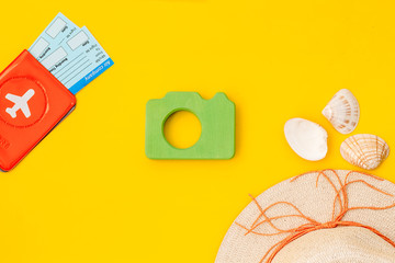 Funny vocation concept with camera, hat, passport and tickets on yellow background top view