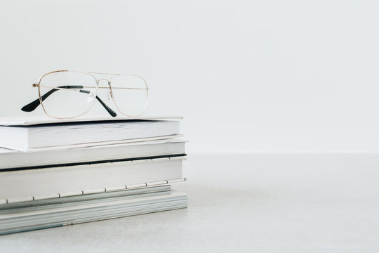 Front view of glasses on notebook and books stack. Minimalist education / business hero header background.