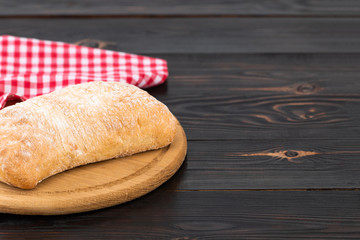 Loaf of ciabatta bread on a cutting board on the dark wooden table