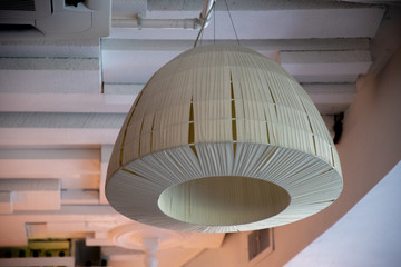 Simple white lampshade of minimal style ceiling lamp. Geometric 3D shape on textured wooden planks...