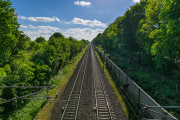 Bahn Gleise, Schienen führen gerade zum Horizont bei blauem Himmel durch grüne Natur