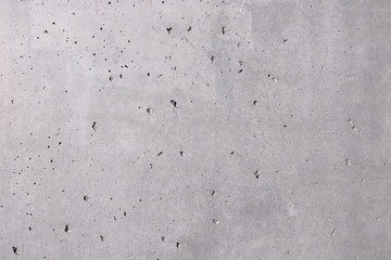 Grauer Hintergrund, Steinwand in grau mit locker verteilten löcher und leicht rauer Oberfläöche als Hintergund und Textur. Betonwand Índustrial Design.