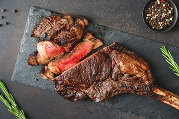 Top view of dry-aged marble beef steak Tomahawk on black slate with spices. Flat lay, dinner...