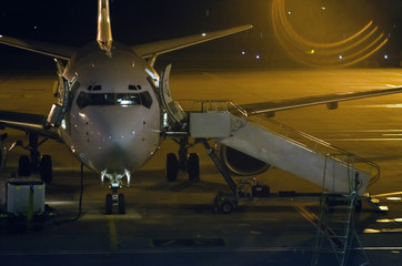 Fototapeta premium Airplane and passenger steps of the vehicle on the platform of the night airport