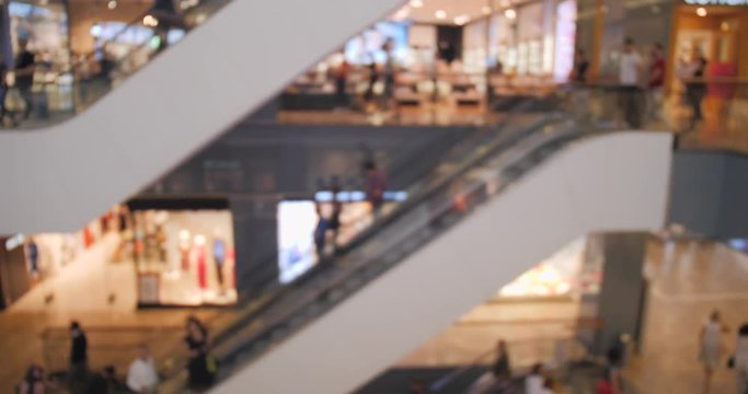 Customers on escalator in a shopping mall out of focus, blurred.