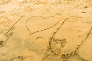 Feet stand near the sign - I heart of you. Summer vacation sand beach inspire to travel on Valentines day.  Romantic travel for love couples or family holidays. Relaxing sign I love you on yellow sand