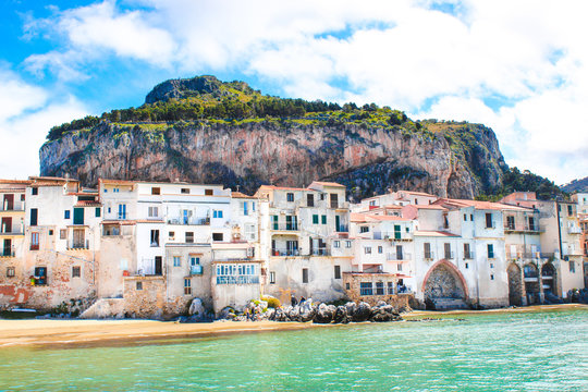 Amazing old houses on the coast of Tyrrhenian sea in beautiful Cefalu, Sicily, Italy. Behind the buildings marvelous rock overlooking the coast. The Sicilian city is a popular tourist attraction