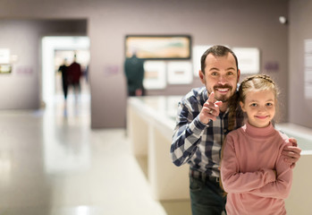 Father and daughter looking at paintings in halls of museum