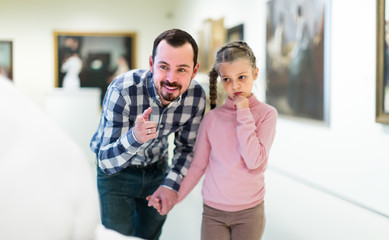 satisfied father and daughter regarding paintings in museum