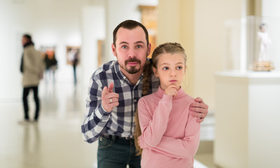 Smiling male and small girl looking paintings